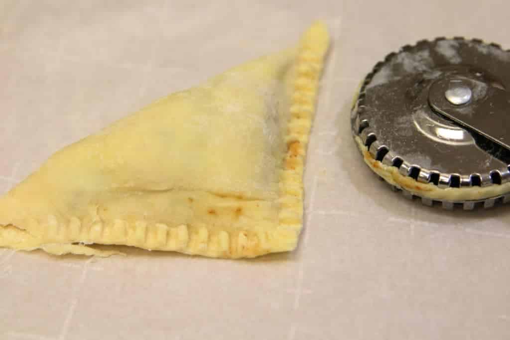 Puff pastry apple pie bite folded corner to corner and crimped, ready to bake