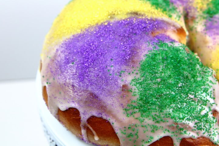 close up of Mardi Gras King Cake with frosting dripping down the sides