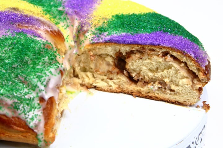 Mardi Gras King Cake with a slice removed showing the cinnamon swirls in the middle
