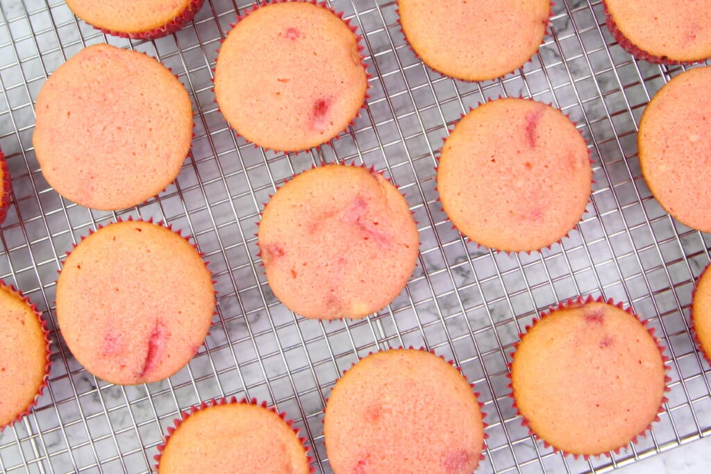 Strawberry cupcakes on a cooling rack after being baked