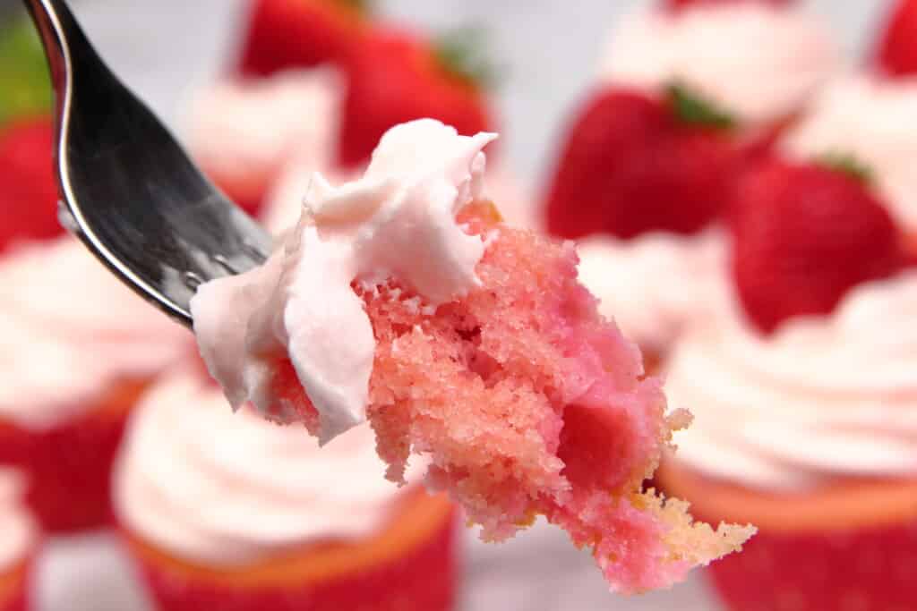 Closeup of a bite of strawberry cupcakes with strawberry buttercream