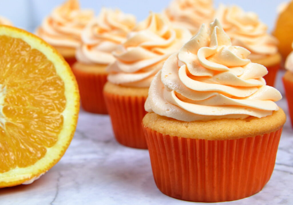 Orange Creamsicle Cupcakes next to a fresh orange cut in half