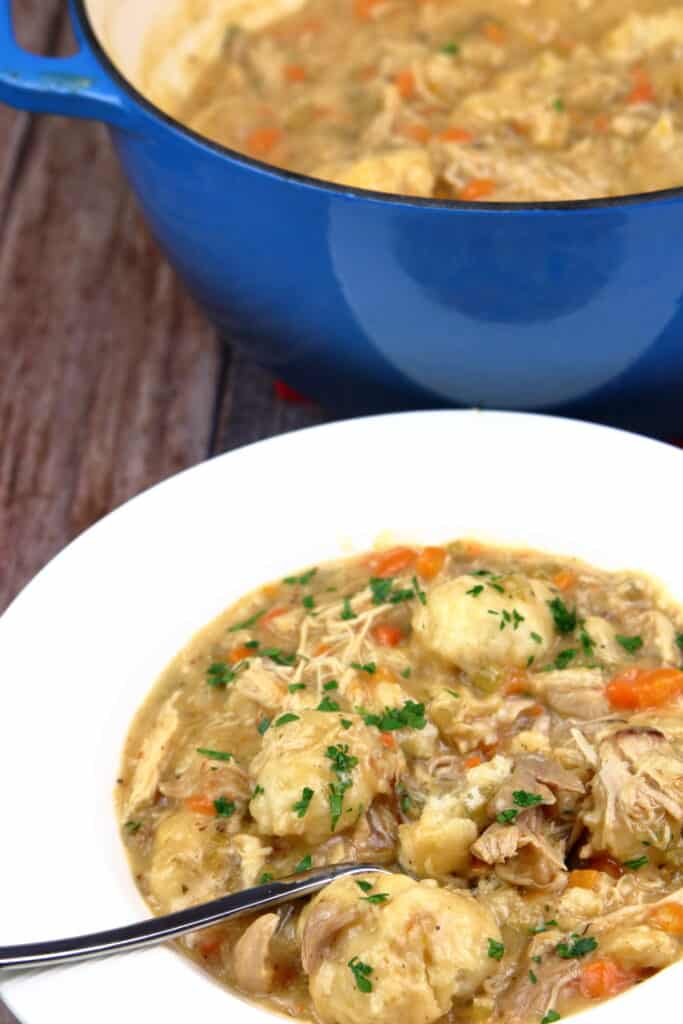 chicken and dumplings in a bowl next to a pot
