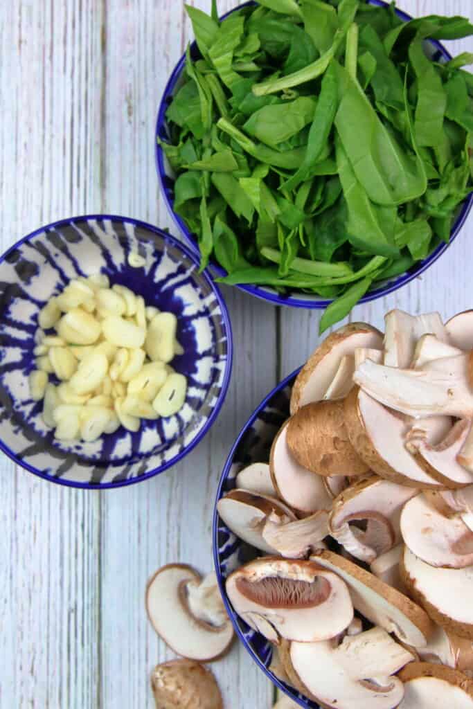 Bowl of ingredients, chopped spinach, sliced garlic, sliced mushroom