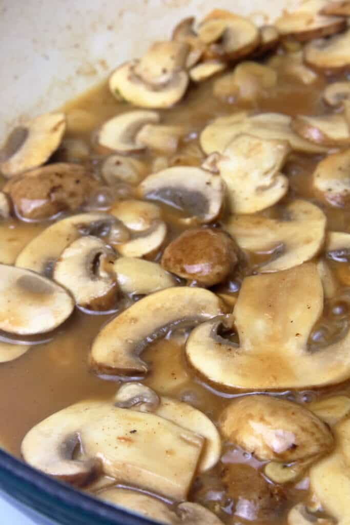 Sliced mushrooms simmering in white wine.