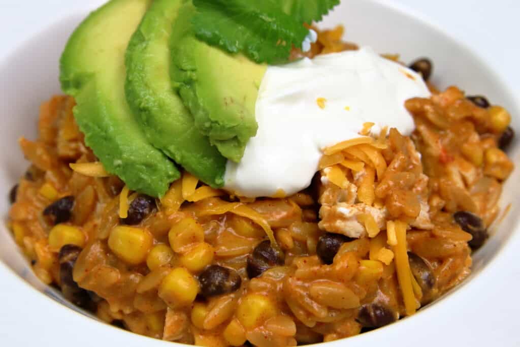 Cheesy Chicken Enchilada Bowl with sliced avocados and sour cream on top