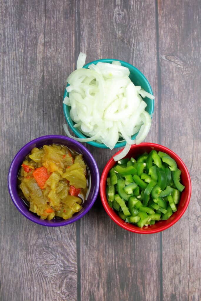 Peppers, onions, and green chile in prep bowls