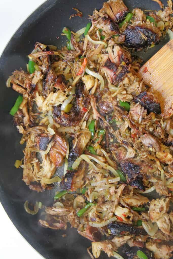 Pulled pork, peppers, onion, and green chile sauteing in a hot pan
