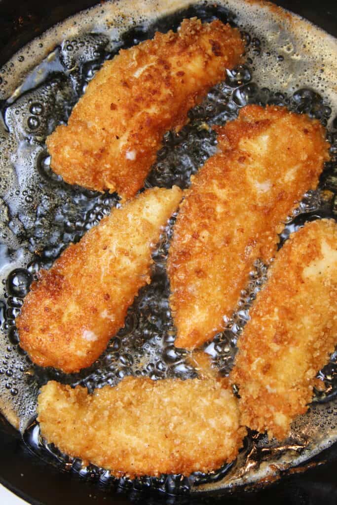 Homemade chicken tenders frying in grease