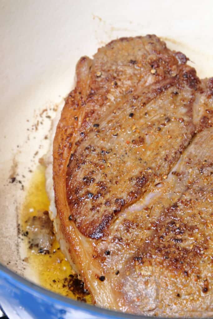 Seared chuck roast in a large dutch oven