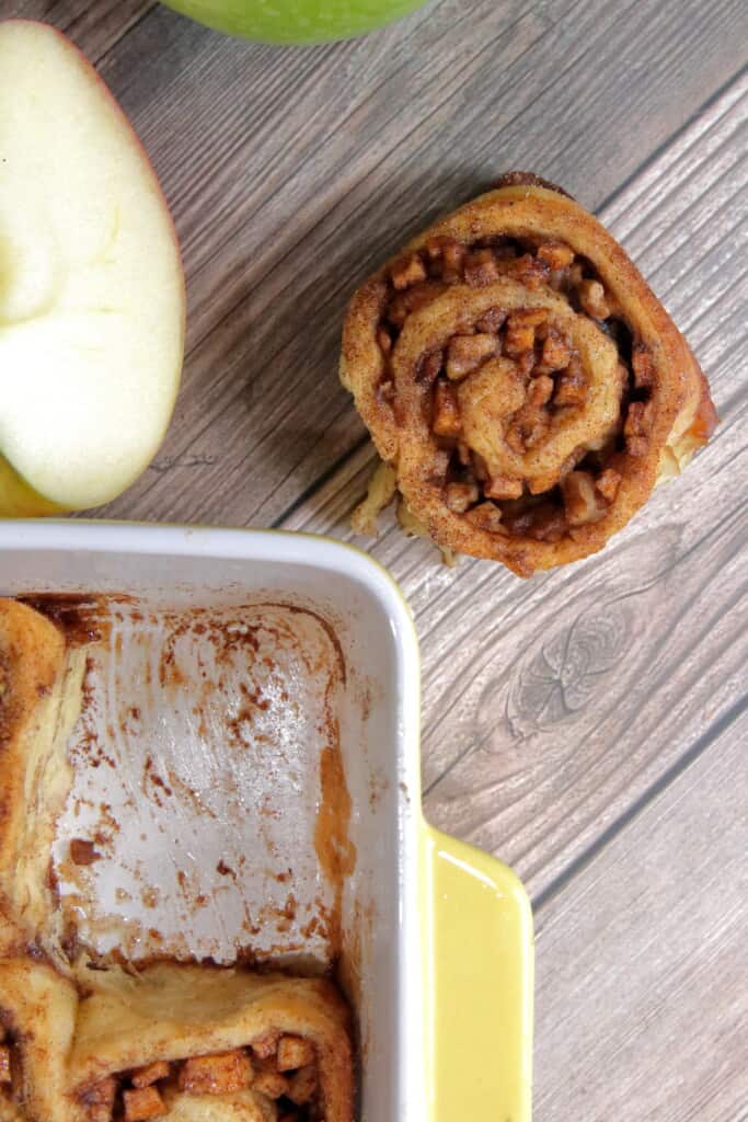 Apple pie cinnamon roll removed from pan on a table.