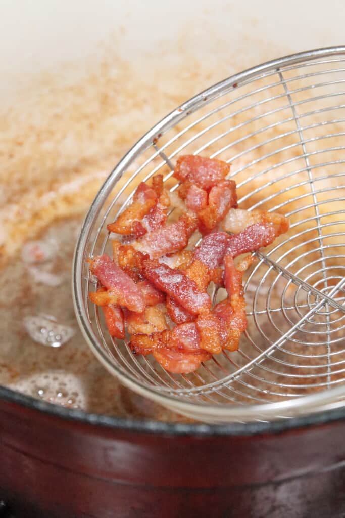 Close up of chopped bacon after it has been cooked. Removing the bacon from the pan and leaving the oil behind