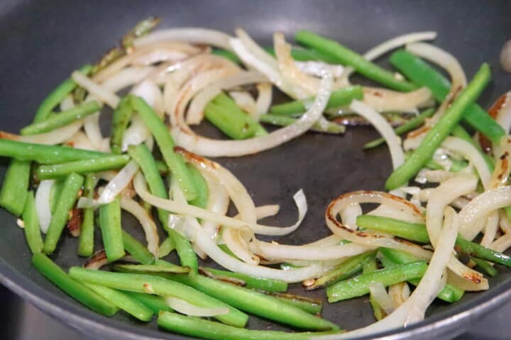 green peppers and white onions sauteed in a pan