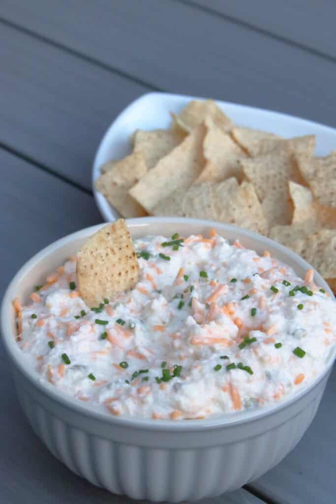 Bowl of mixed onion dip with a tortilla chip sticking in the dip.