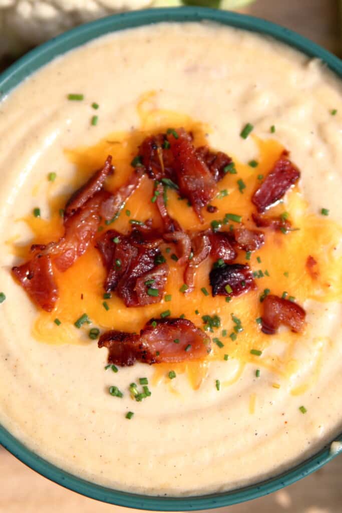 Close up of a bowl of loaded cauliflower soup with bacon, cheese, and chives
