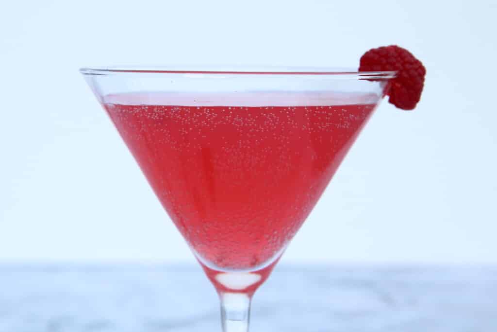 Closeup of the raspberry martini with a raspberry garnish and a clean white background
