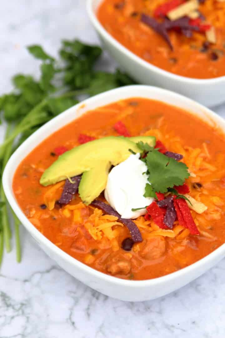 closeup of a bowl of chicken enchilada soup with all the toppings
