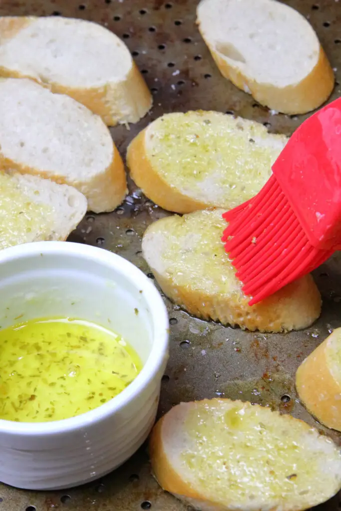 Brushing melted butter on the baguette slices prior to toasting