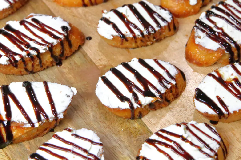 goat cheese spread on crostini with drizzles of balsamic glaze