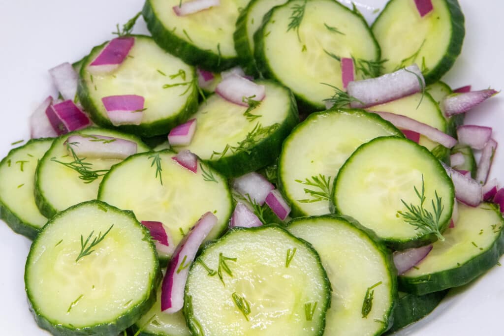 sliced cucumbers, dill, and diced onions in a bowl