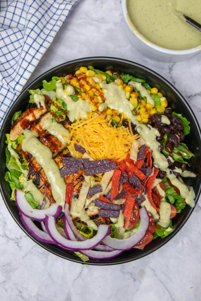 Close up of southwest chicken salad topped with all the ingredients plus BBQ and Avocado ranch