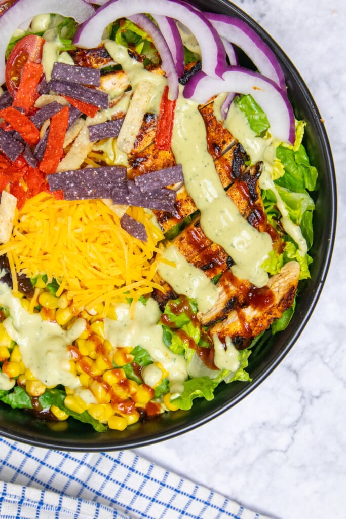 Close up of southwest chicken salad topped with all the ingredients plus BBQ and Avocado ranch
