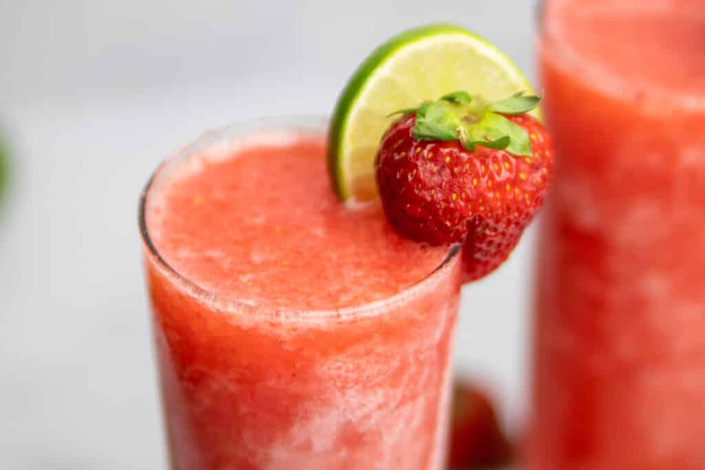 close up of the Frozen Strawberry Limeade Vodka with fresh lime and strawberry for garnish