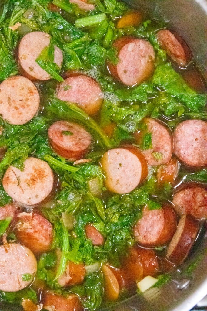 All of the ingredients: sausage, onions, garlic, greens, and stock simmering in a pot