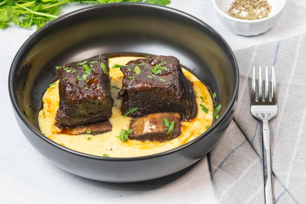 plate of finished red wine braised short ribs over polenta